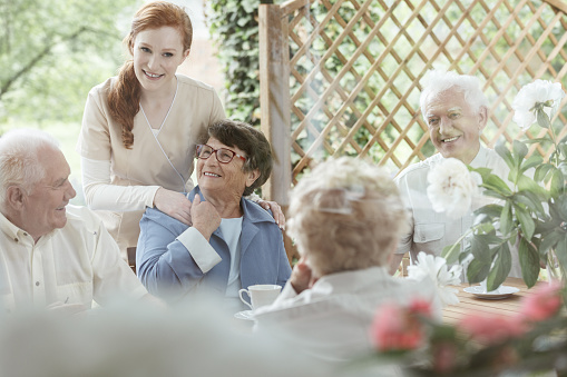 older people sitting outside at a care home around a table