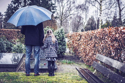 father and daughter viewing a grave