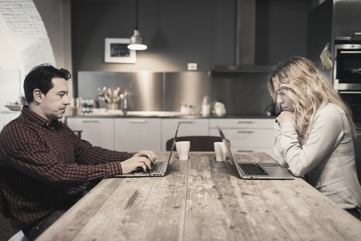 Couple working on laptops at kitchen table